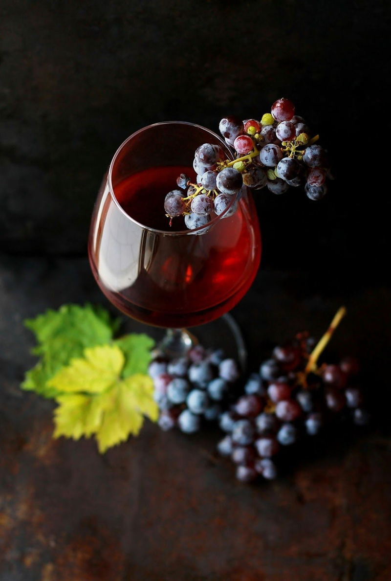 Grapes dangle in a glass of deep red wine