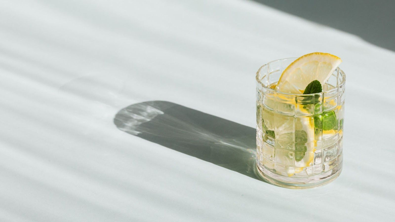 an aperitif in a glass with ice, casting a shadow on a white surface, featured in Villa Pereire’s blog on how to host an apero, a French happy hour